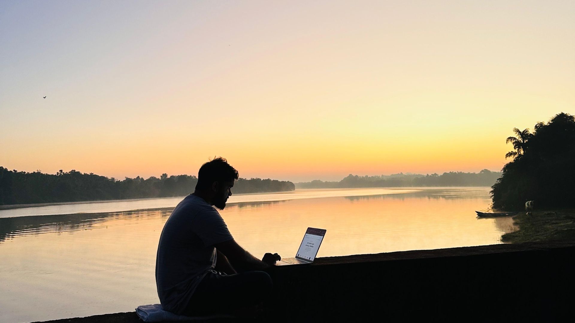 web designer sitting near a river in mangalore with laptop